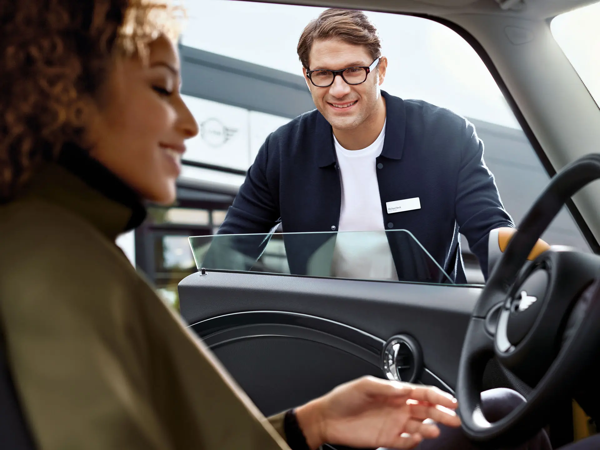 MINI employee greets service customer.