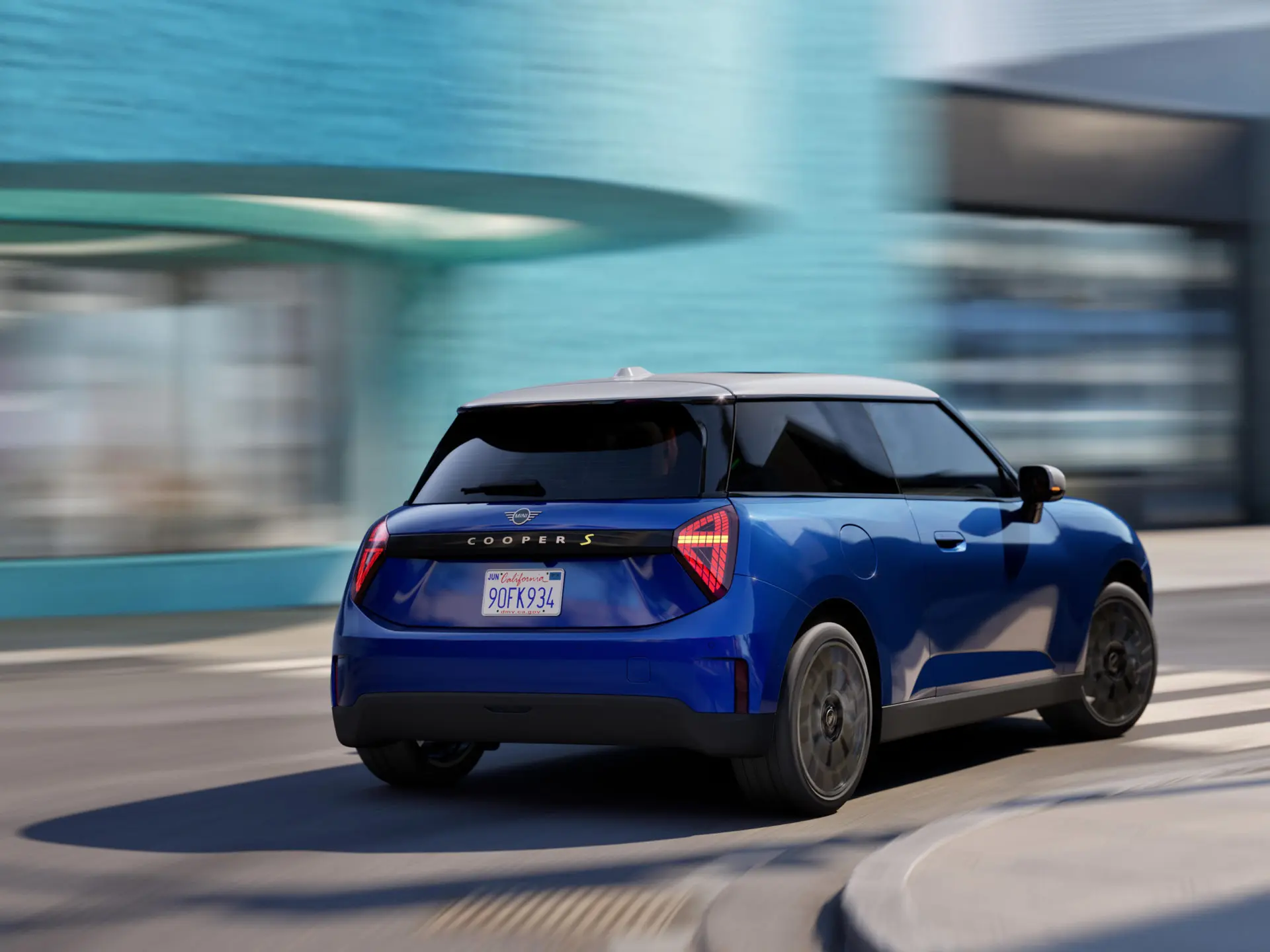 A MINI Cooper drives dynamically around the curve.