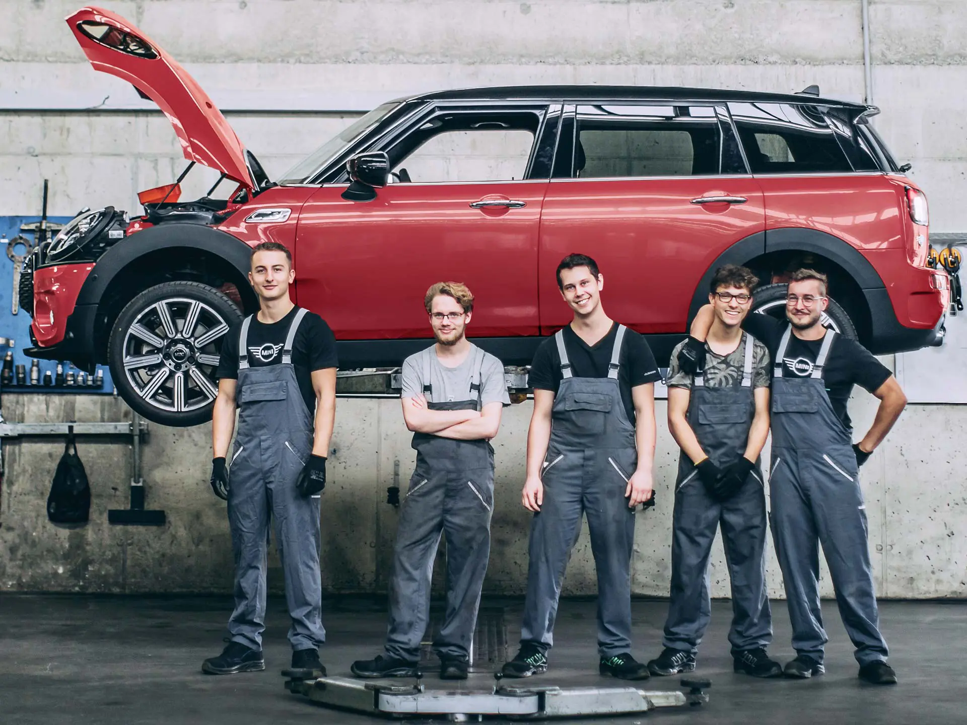 MINI service employees in front of a MINI Countryman on a lift.